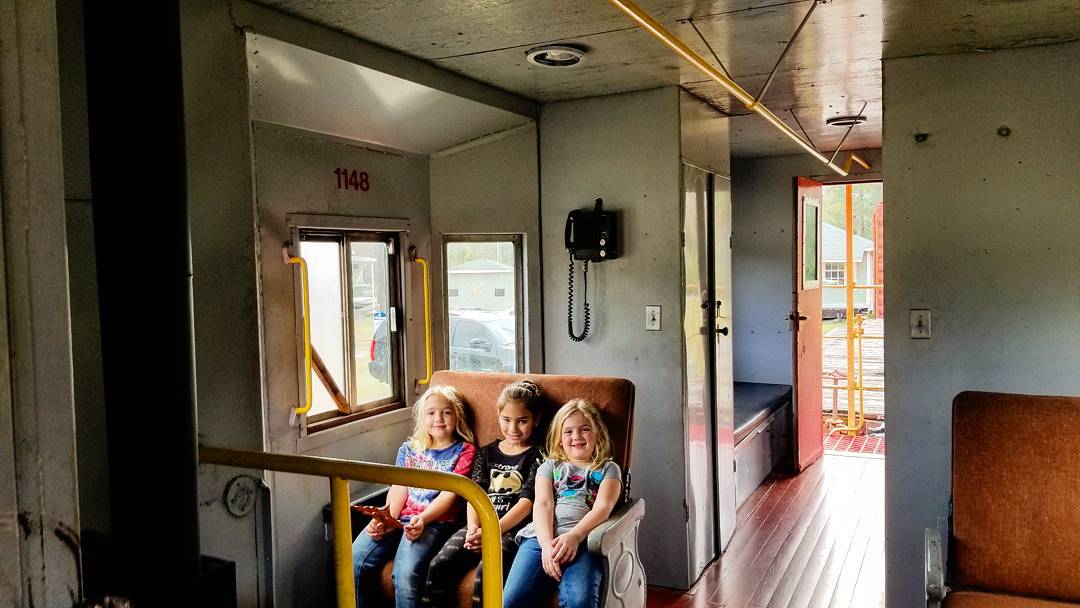 Kids sitting in old train car. 