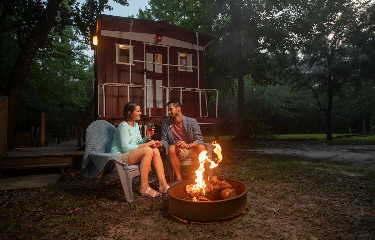 a couple sitting at a campfire in front of Katy's Kaboose