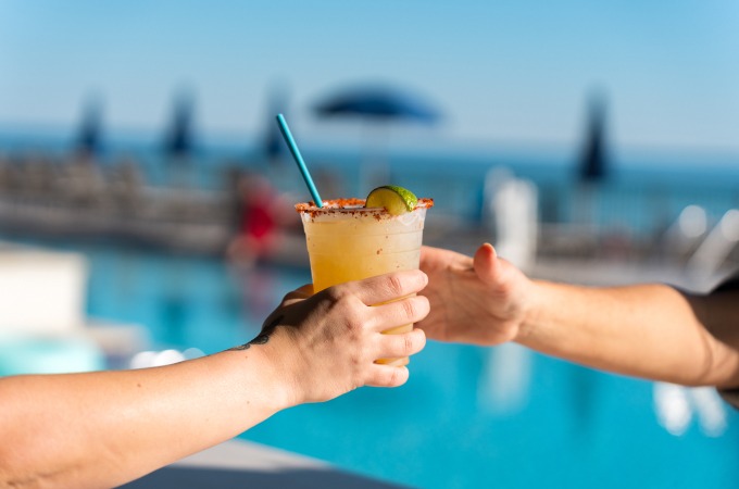 server hands cocktail to guest poolside